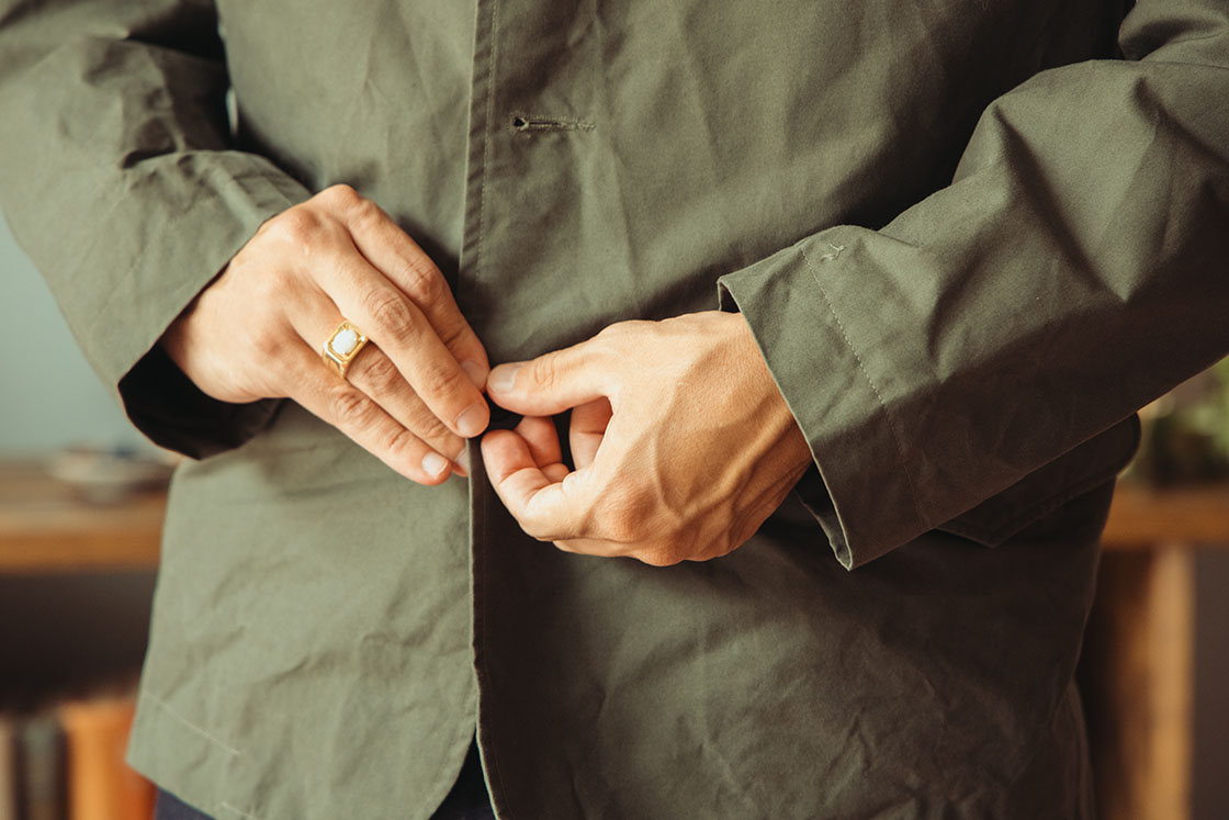 Image of model wearing Conkers Rambler Blazer in Seafoam with hands messing with suiting buttons