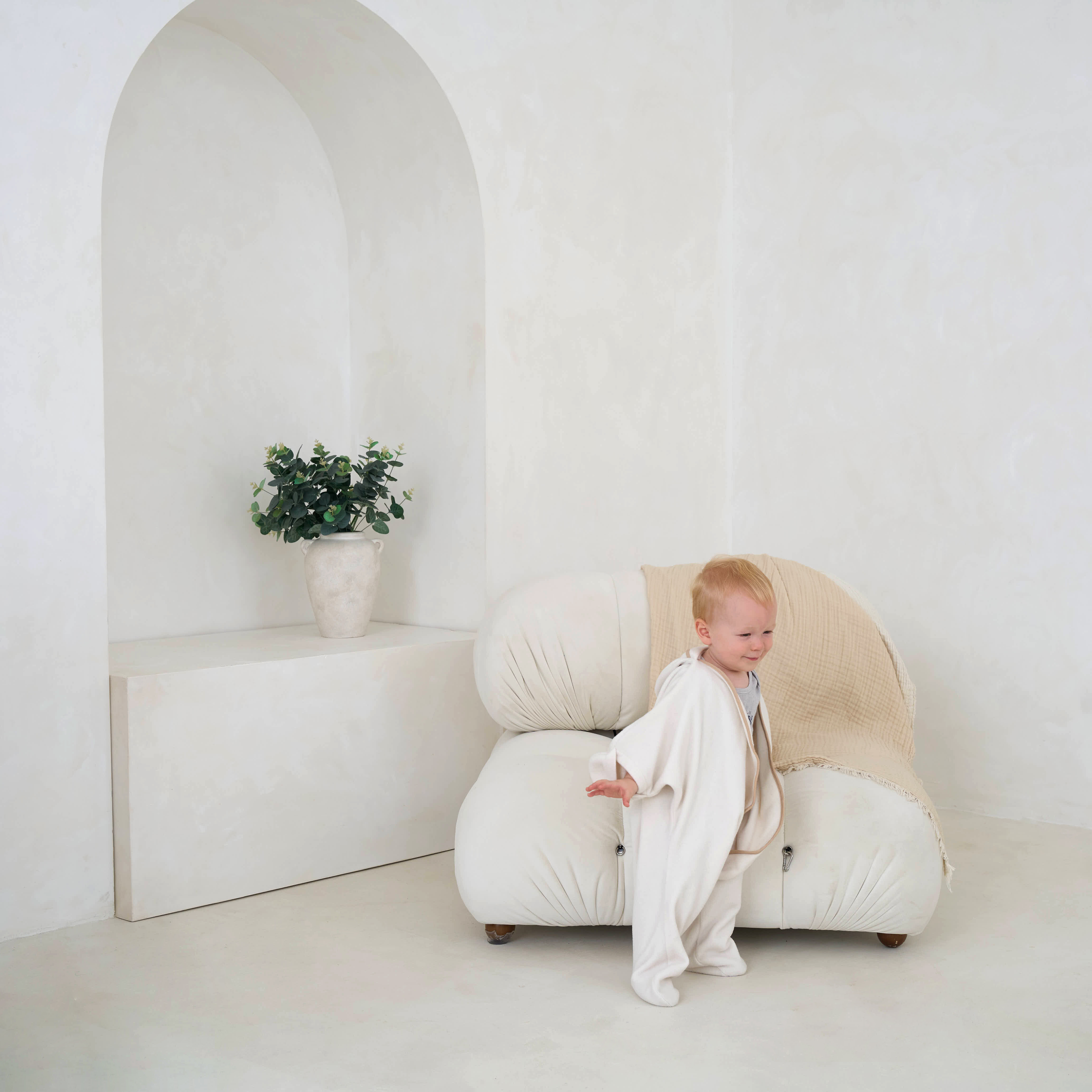 Toddler stood by a chair wearing the cream clair de lune star fleece wrap blanket