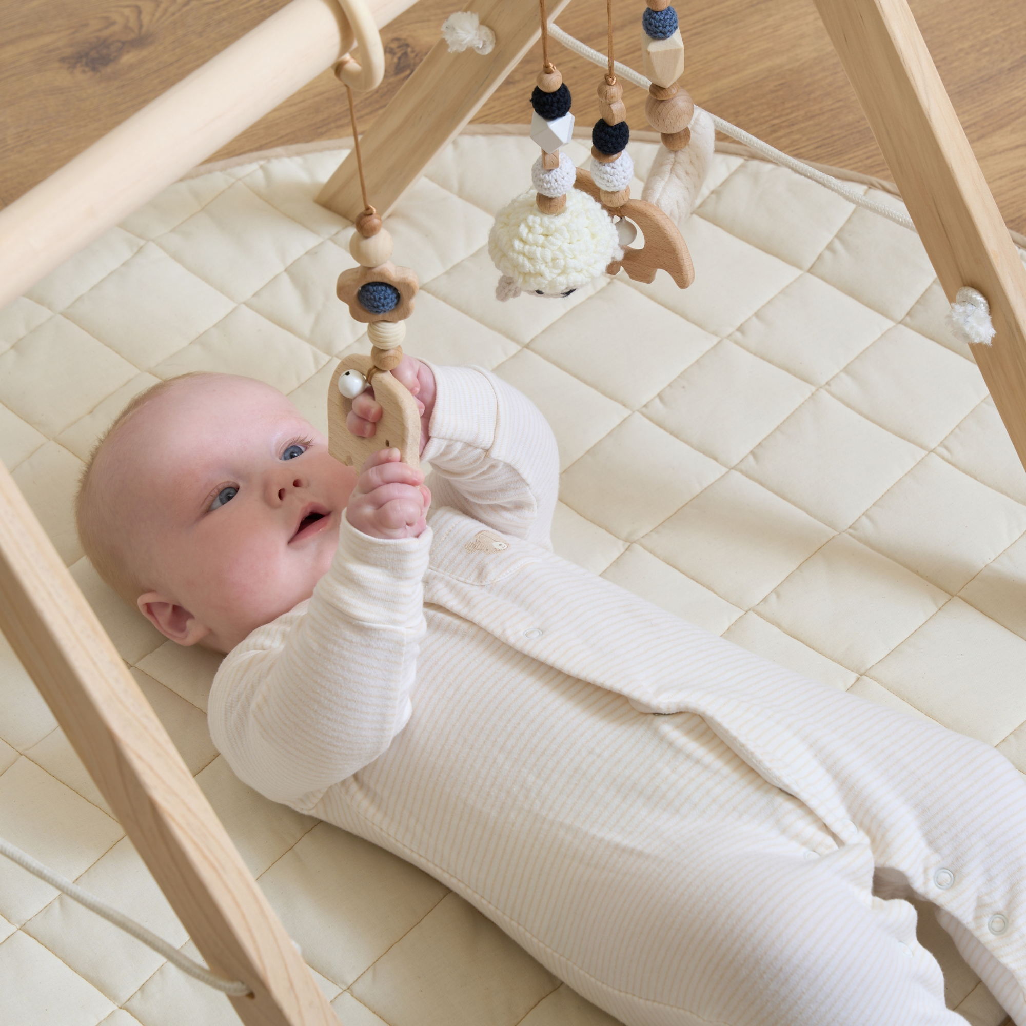 Organic Play Mat & Wooden Play Gym Set by a grey sofa and glass coffee table in a bright white ultra stylish living room | Baby Play Mats & Gyms | Baby Tummy Time Toys - Clair de Lune UK
