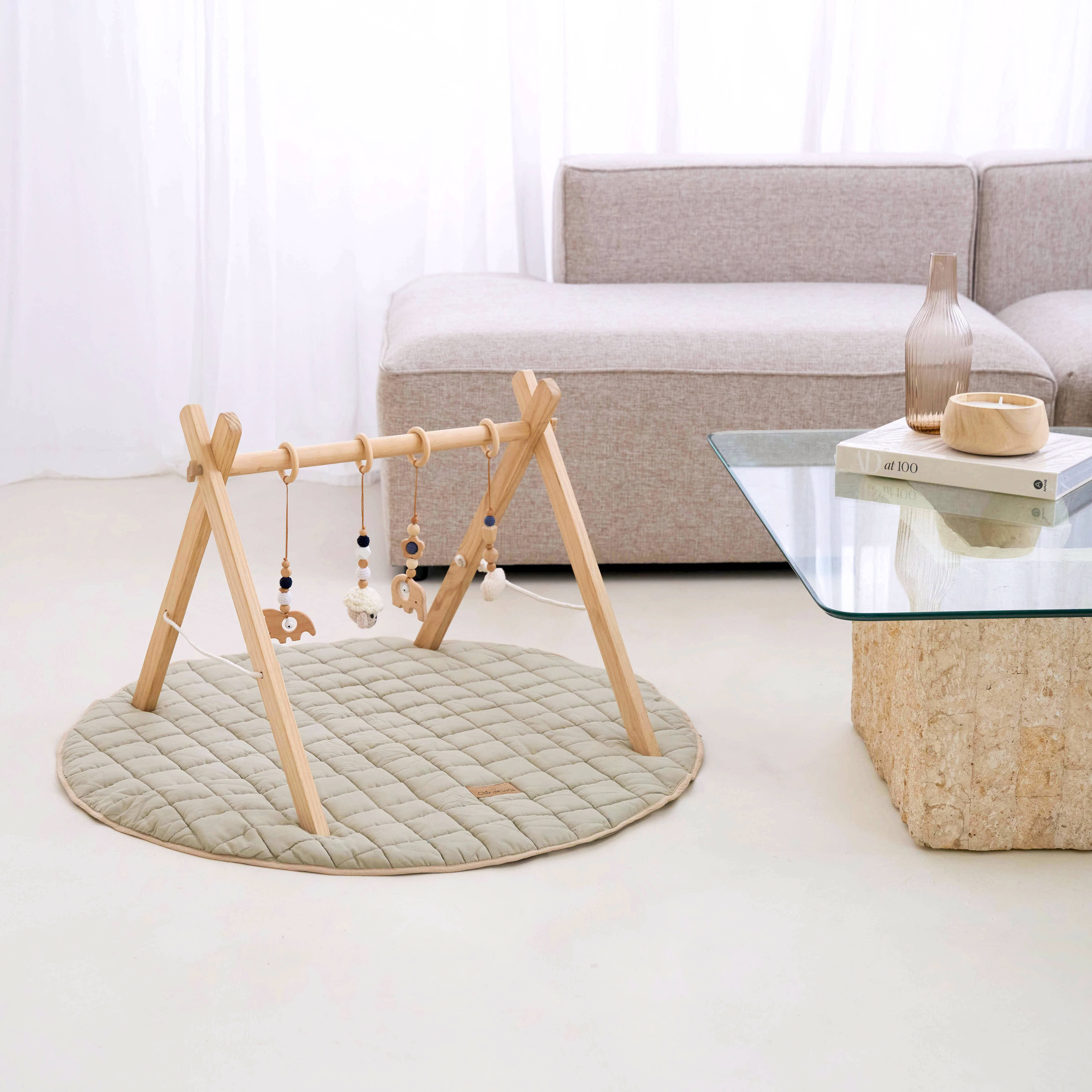 Organic Play Mat & Wooden Play Gym Set by a grey sofa and glass coffee table in a bright white ultra stylish living room | Baby Play Mats & Gyms | Baby Tummy Time Toys - Clair de Lune UK