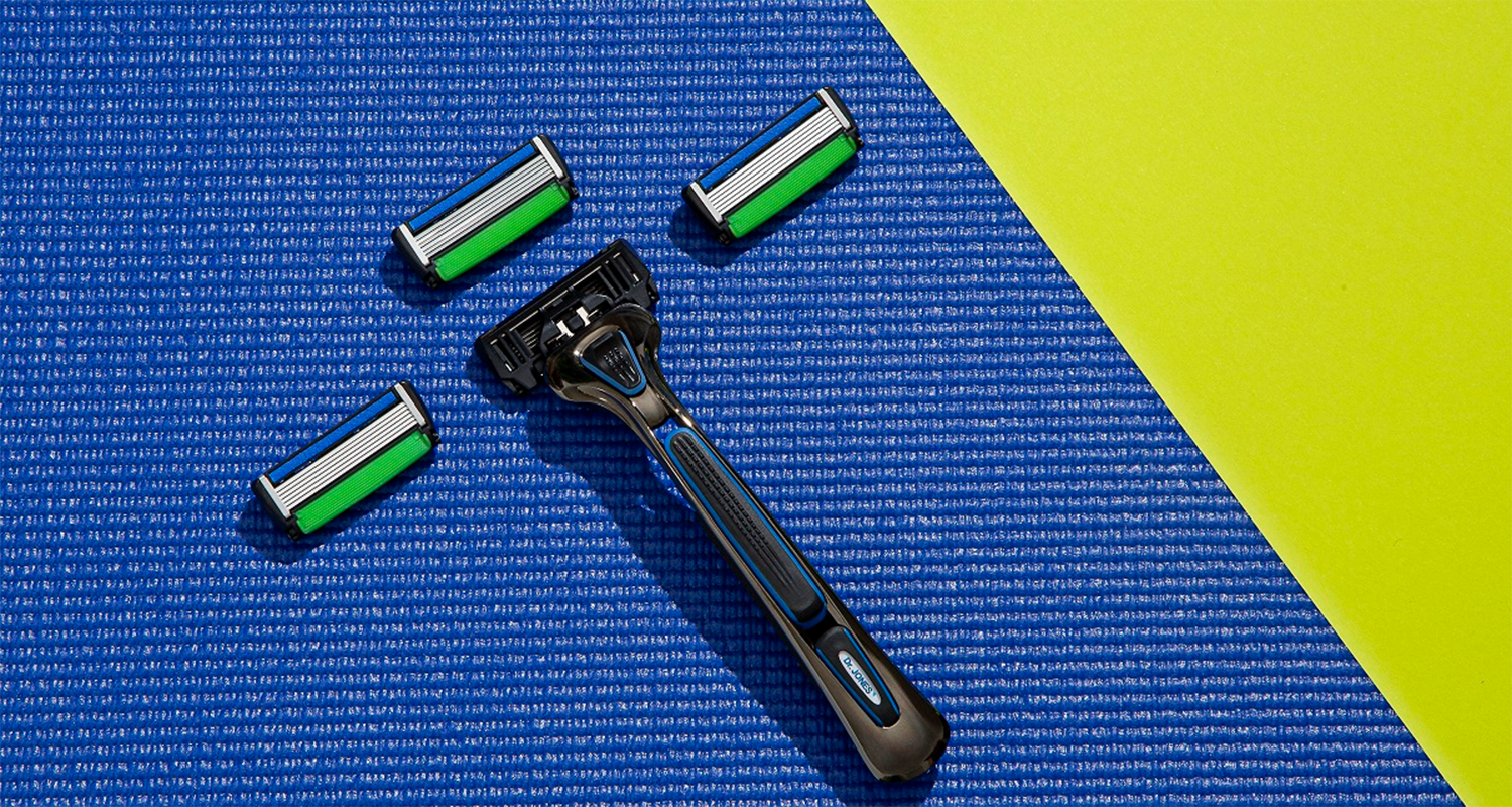 Em artigo sobre funcionalidades secretas do THE RAZOR, da Dr. JONES, imagem traz o aparelho de barbear com três lâminas em fundo texturizado azul e verde limão.