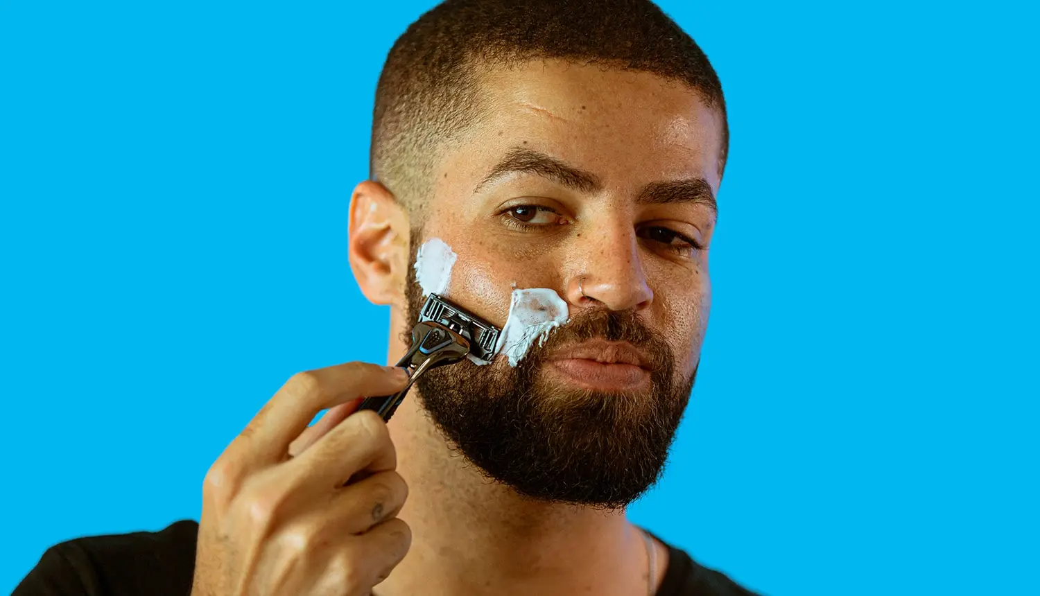Em fundo laranja e marrom-claro, foto mostra uma mão de pele clara segurando a embalagem do esfoliante Isotonic Face Scrub, da Dr. JONES.