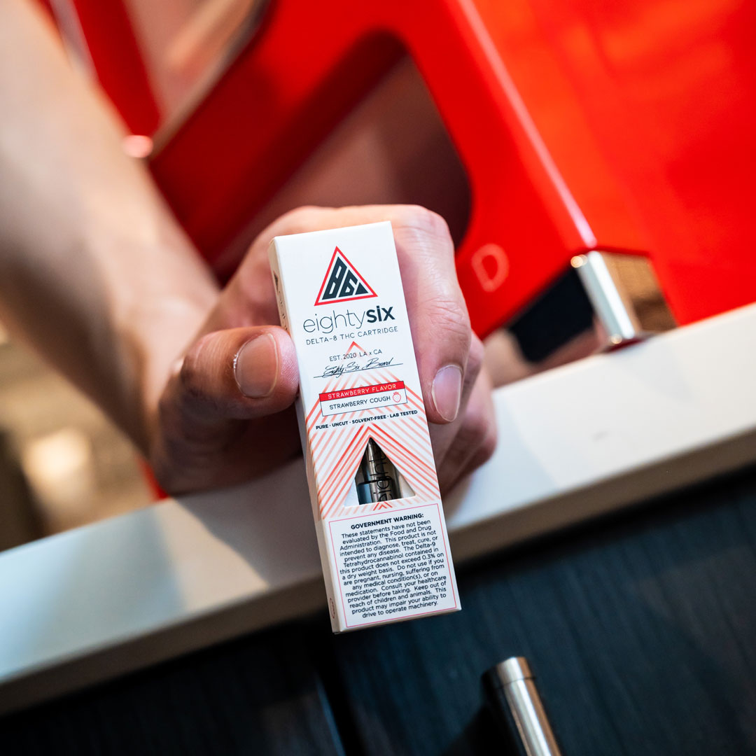 Person holding an Eighty Six vape cartridge box