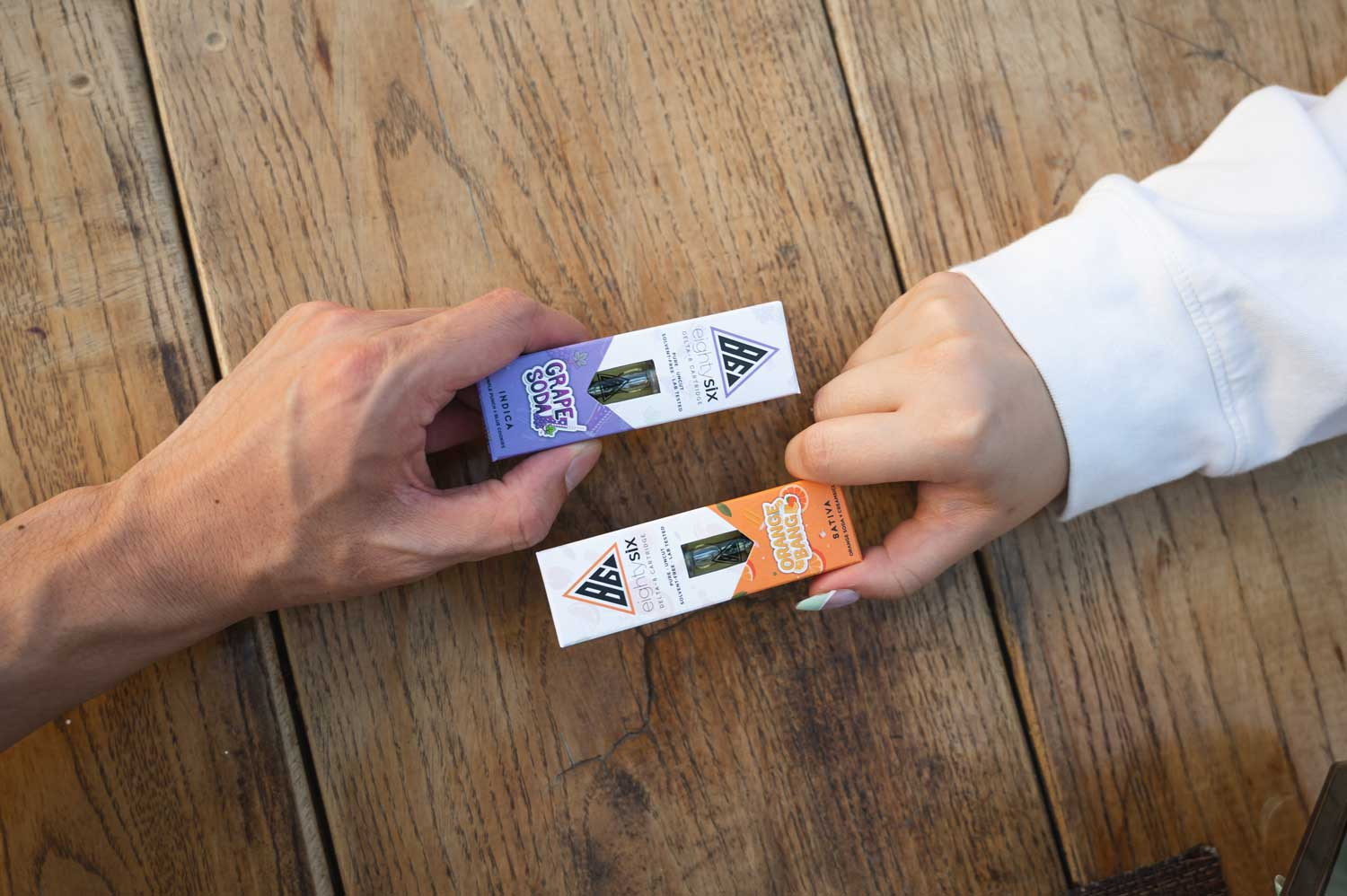 Hands passing Delta-8 vape cartridges