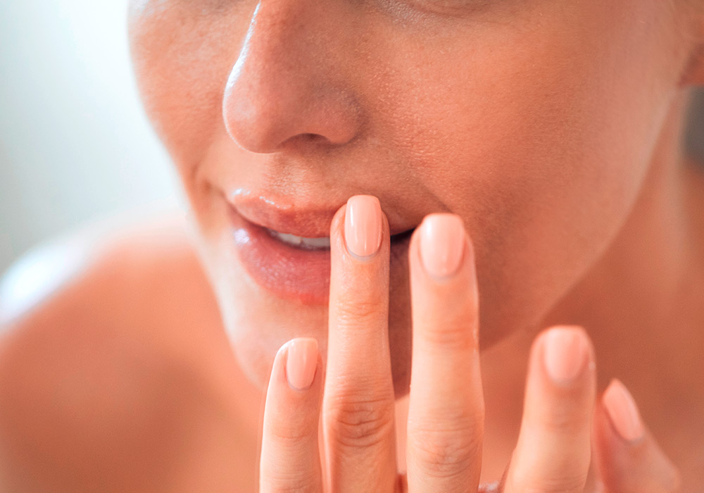 Frau greift sich mit einem Finger an die Lippen