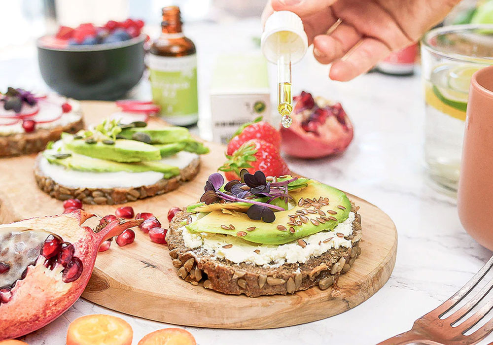 Jemand tröpfelt InnoNature D3 Tropfen auf ein Avocadobrot