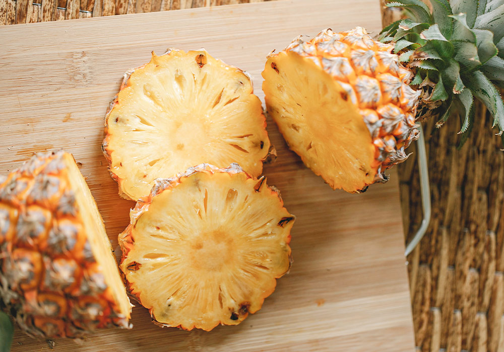 Aufgeschnittene Ananas auf einem Holzbrett.