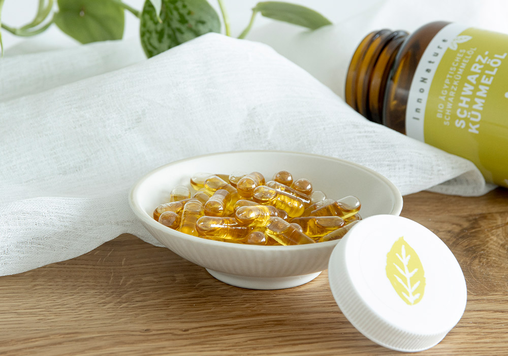 Kleines Schälchen mit mehreren durchsichtigen Kapseln, in denen eine goldene Flüssigkeit (Öl) enthalten ist.