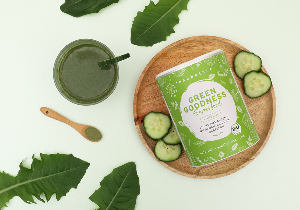 InnoNature Green Goodness Shake auf einem Holztablett mit Gurkenscheiben