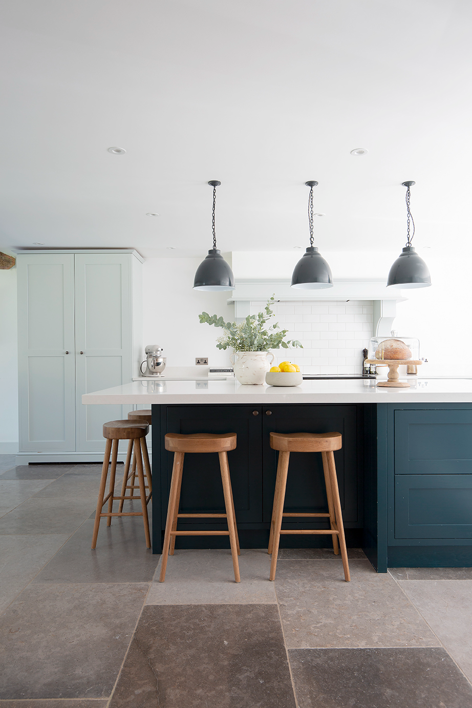 Farrow Grey Natural Stone Tiles in a kitchen with hanging pendant lights and cabinets along the back wall