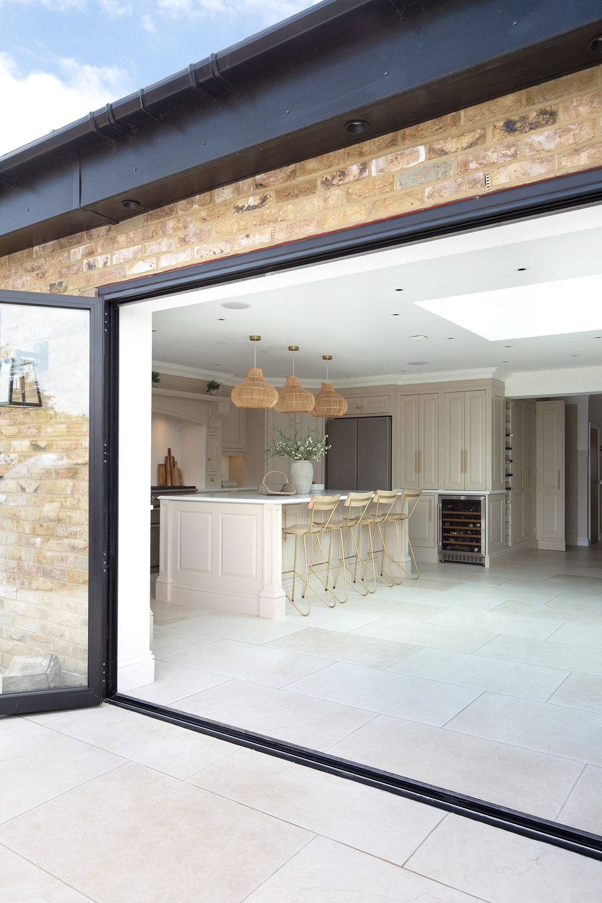A kitchen with an island and a large sliding door with Dorchester Aged white tiles and pavers