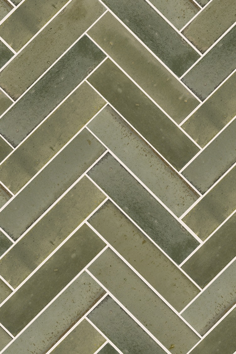 Close-up of Hockley Antiqued Sage metro tiles laid in a herringbone pattern, showcasing textured, muted green tones for modern bathroom tile inspiration.