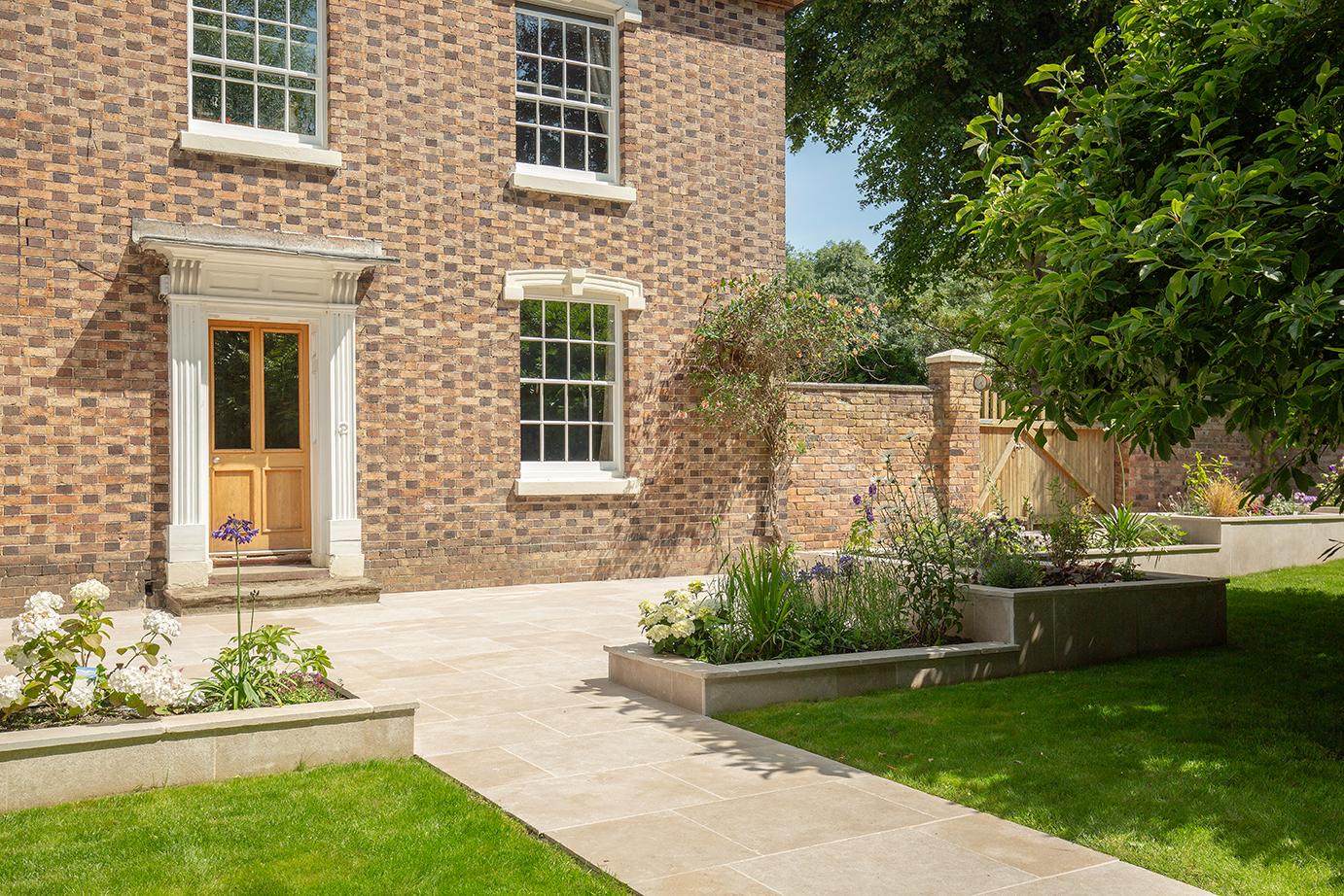 A brick house with Dijon Seasoned patio with a garden and a door