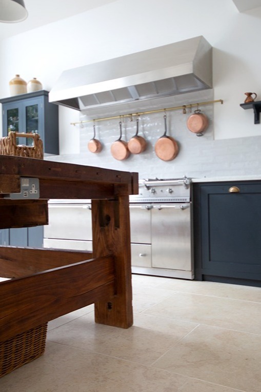 Monte Carlo Limestone flooring in a rustic kitchen with blue units and copper pans 