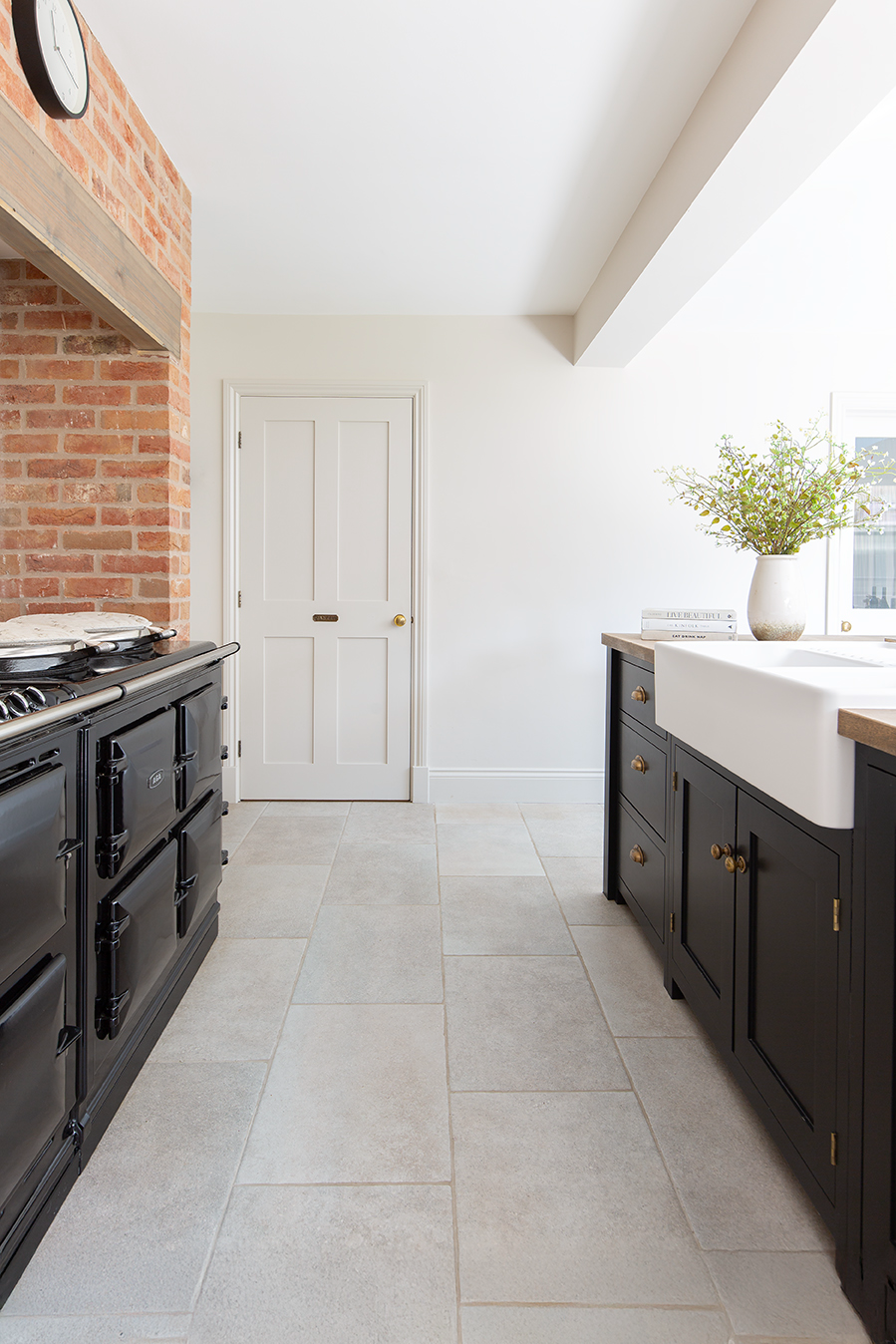 Lullington Grey stone effect floor tiles in a kitchen with blue units and a brick wall 