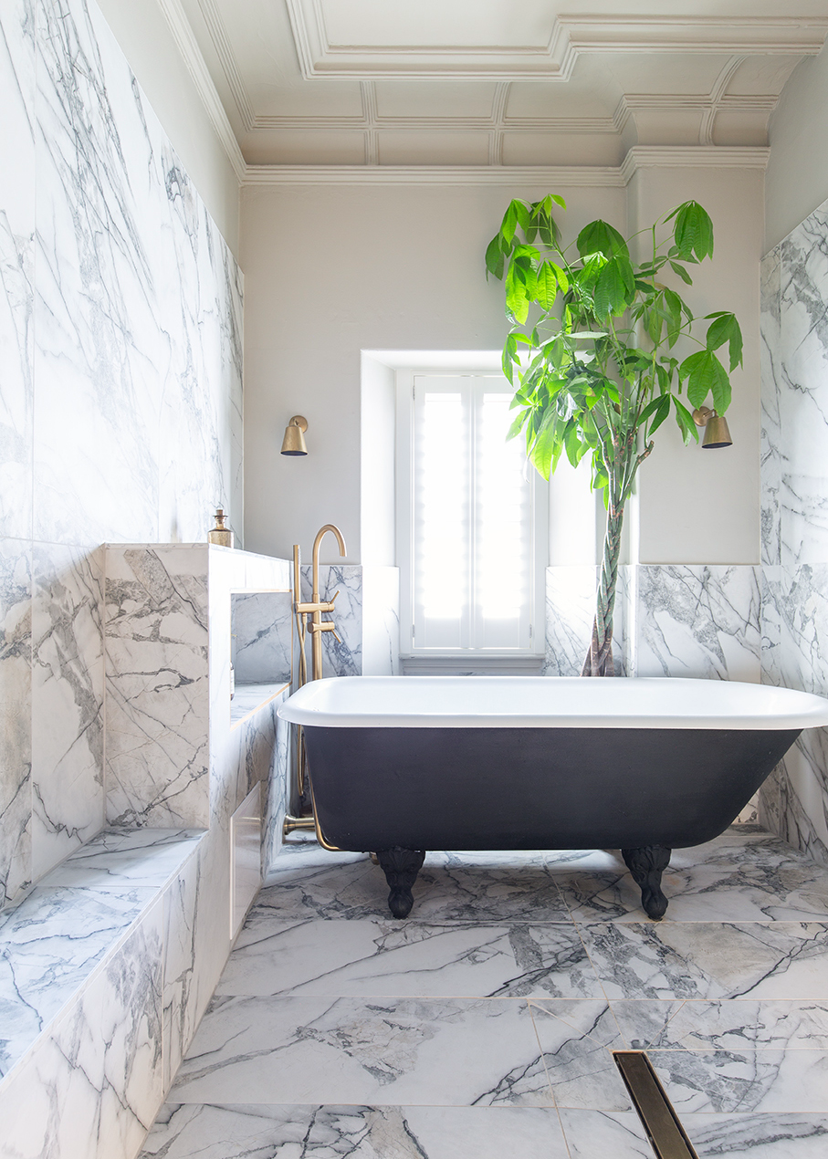 bathroom with a bathtub and a tall plant, featuring Athena White marble effect tiles on floor and wall