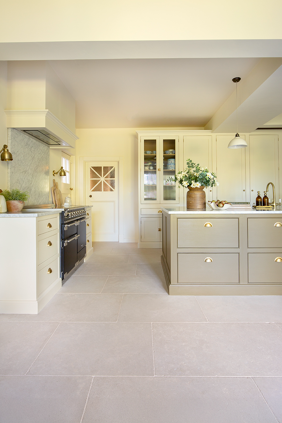 A modern kitchen featuring a spacious island and light natural stone flooring.