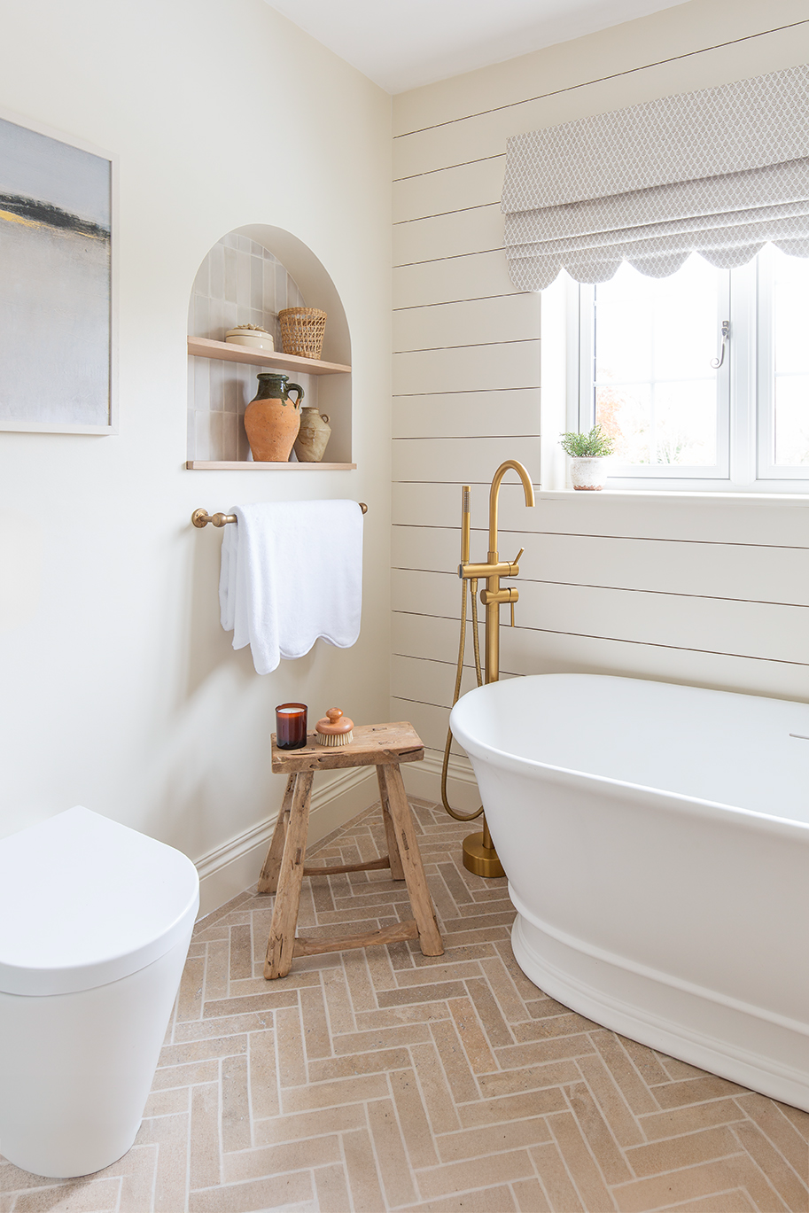 white bathroom with herringbone brick floor and white bath