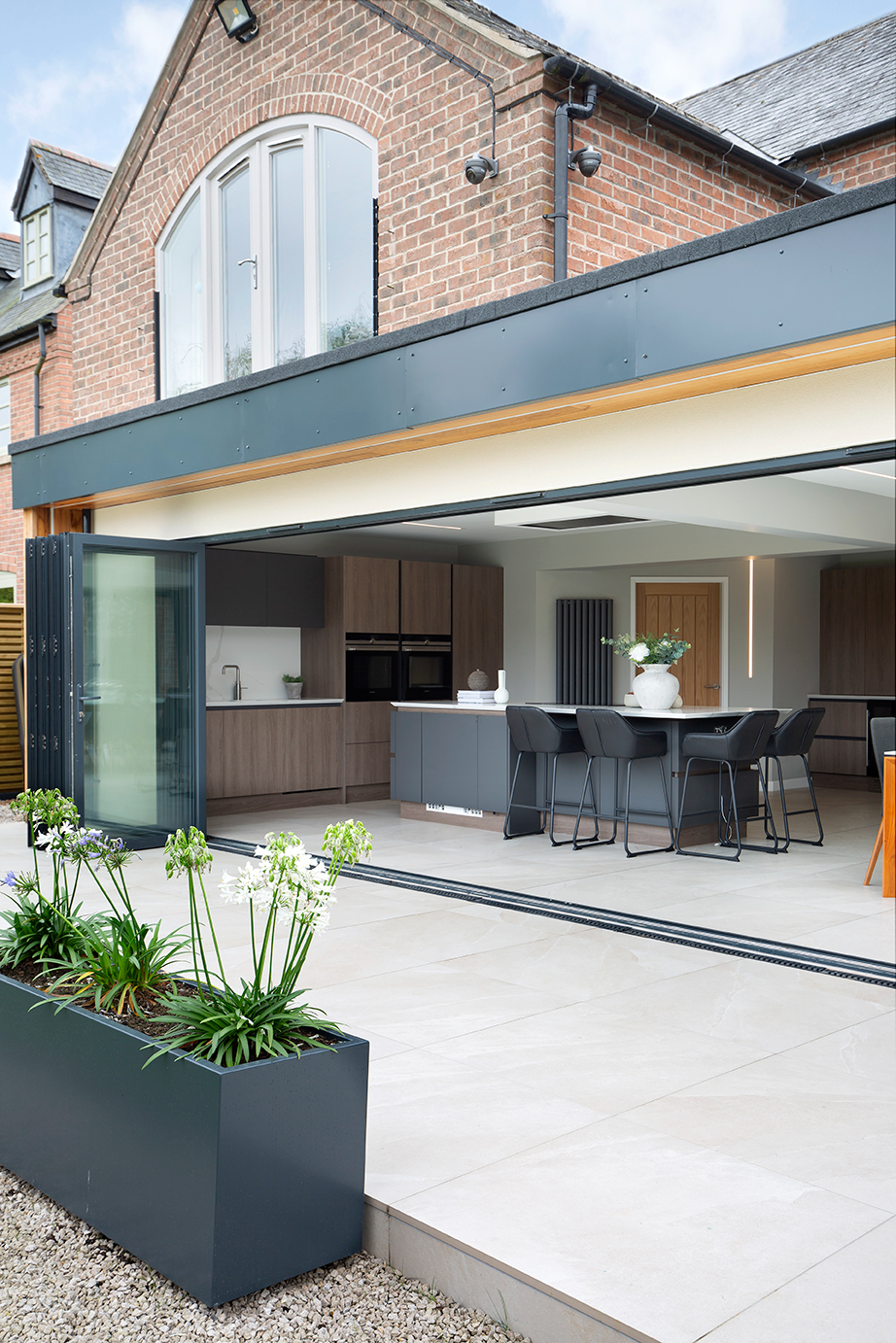 Open plan modern kitchen with porcelain stone effect flooring running through to the garden