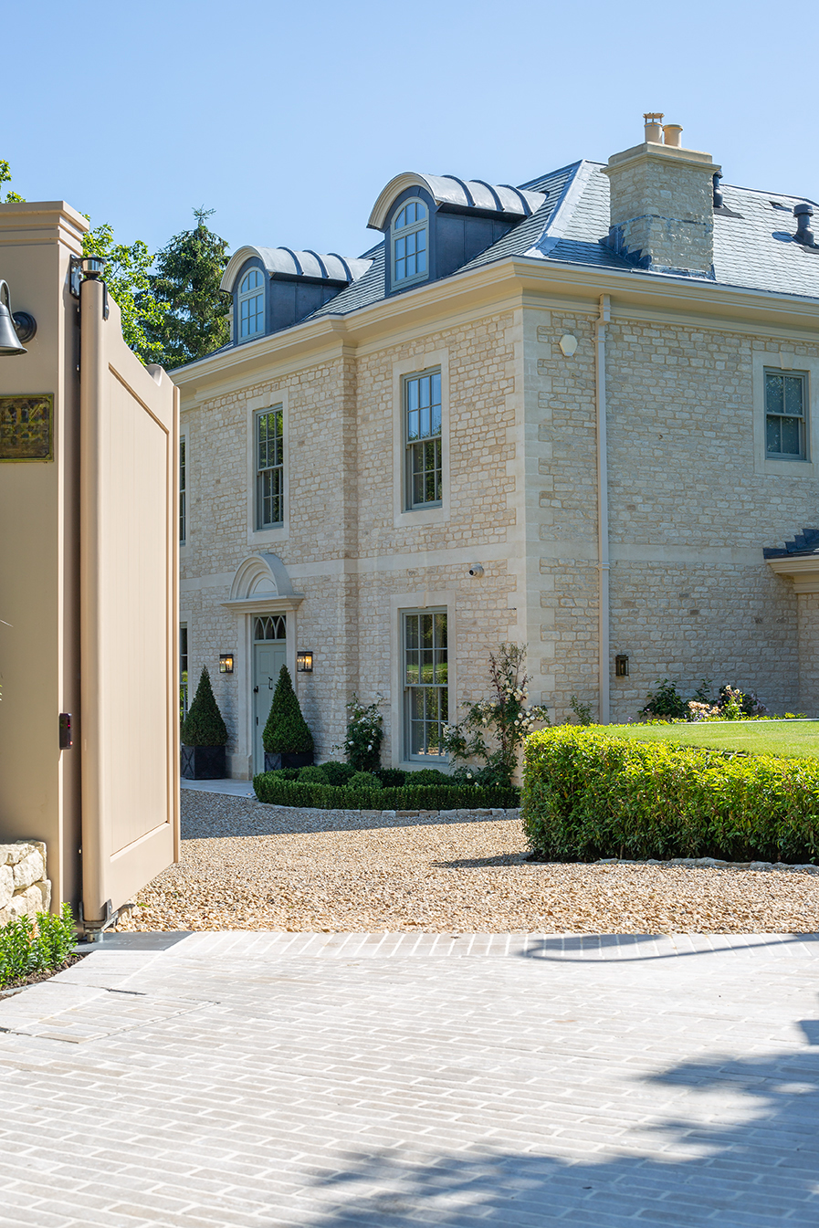 A large brick house with a Dijon Tumbled Herringbone driveway