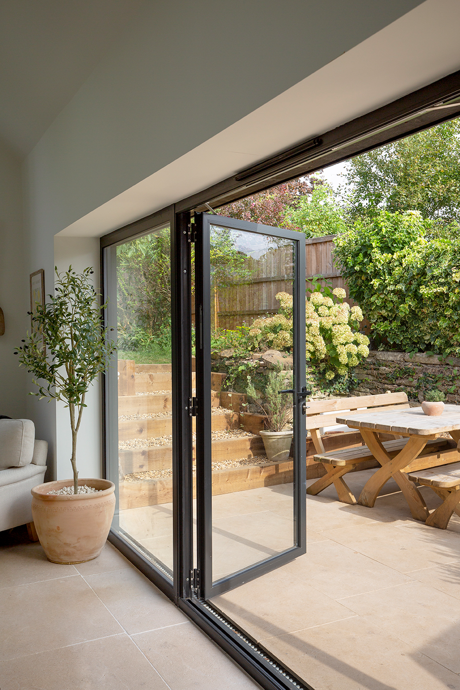 A glass sliding door leading out to the garden with a table and chairs and Tuscany Seasoned tiles