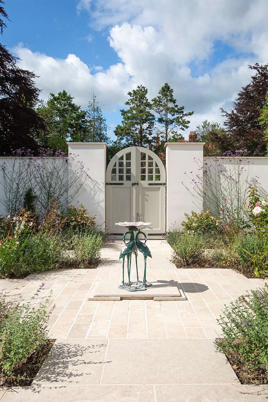 beige stone cobbles in courtyard garden with planting and white wall