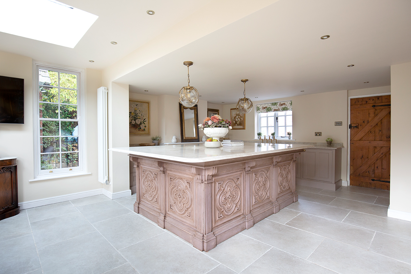 Light pink wooden kitchen island with ivory stone effect porcelain flooring