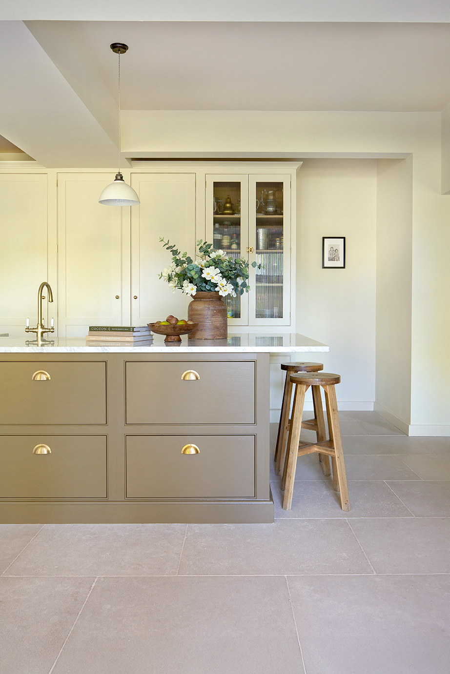 A modern kitchen featuring a spacious island and a single stool for seating.