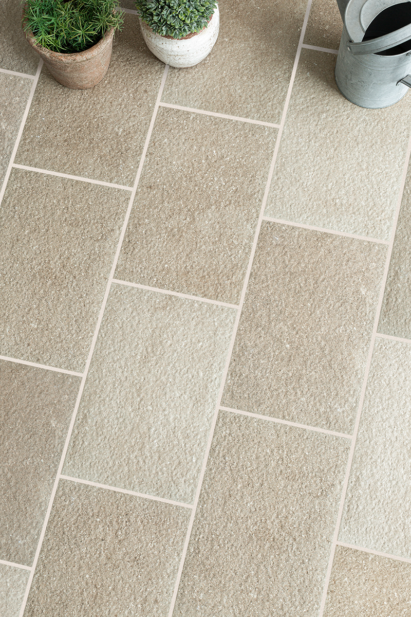Flat lay of Clariston Beige cobbles with a plant pot and watering can