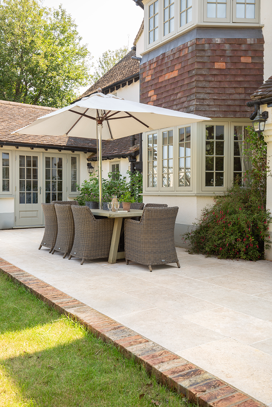 Dijon Tumbled Garden Paving with a table and chair set and a bricked house 