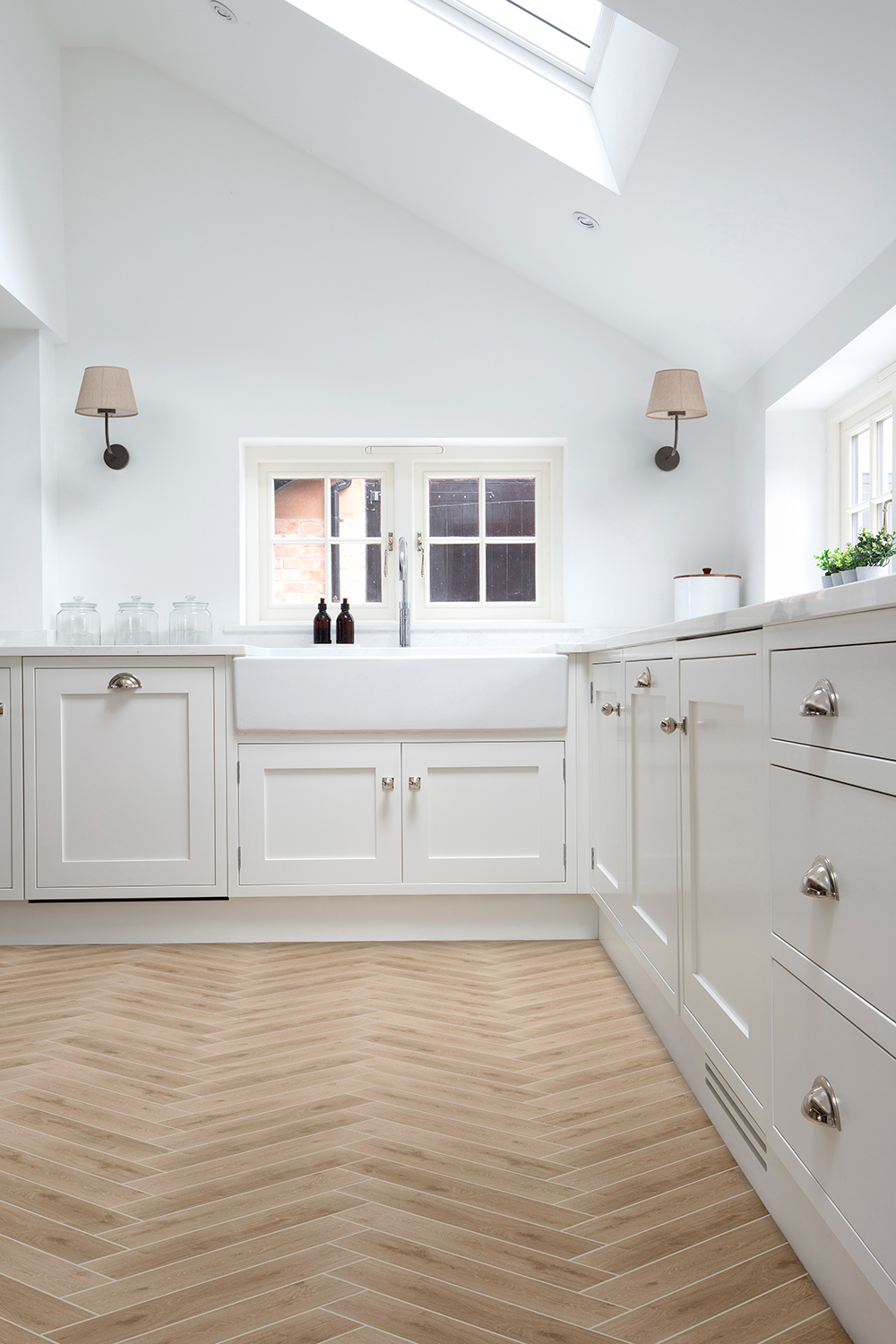 A white kitchen with white cabinets and a window with Eaton Oak herringbone floor