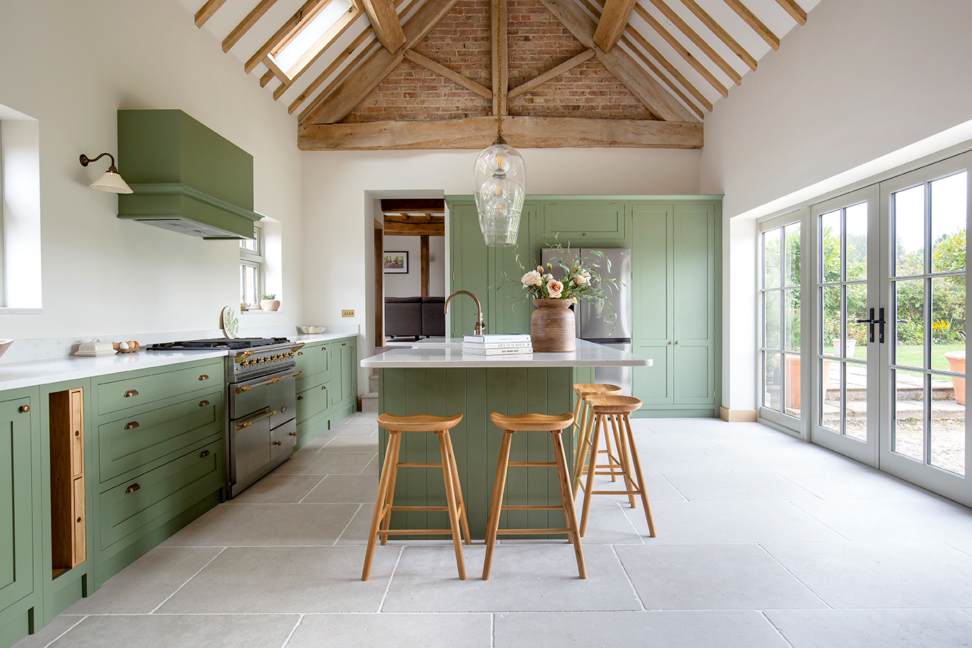 Stone effect porcelain flooring in a large green kitchen with an island
