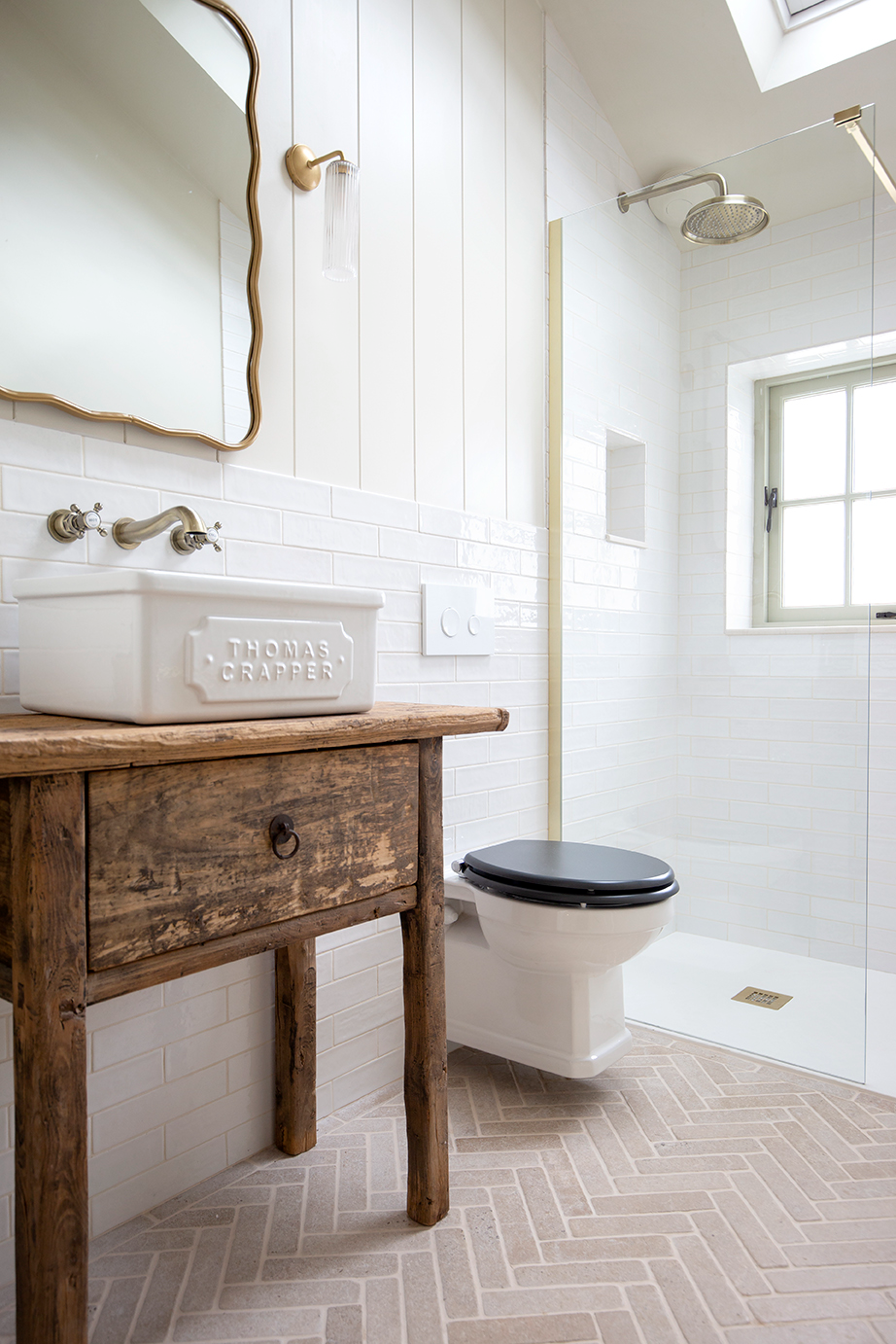 white bathroom with herringbone brick floor and rustic vanity