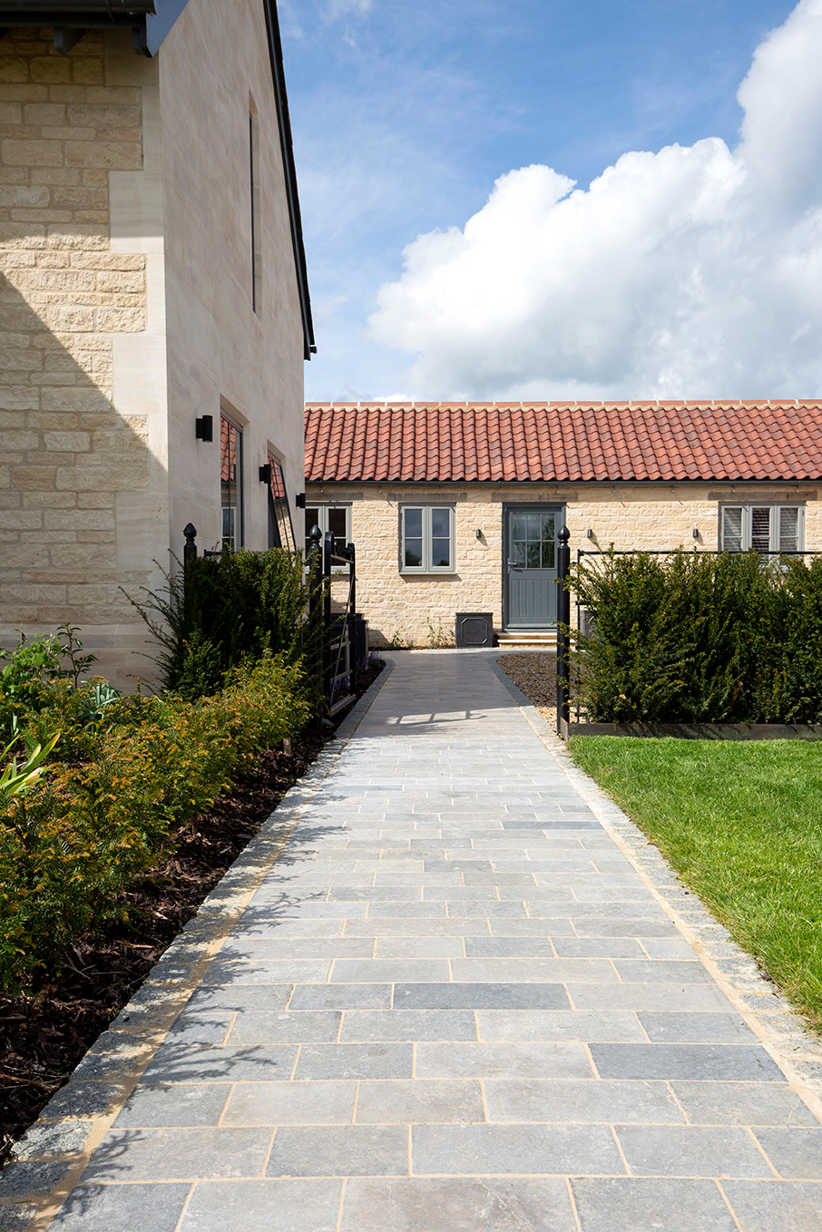 grey limestone cobble path with cotswold stone house and patio