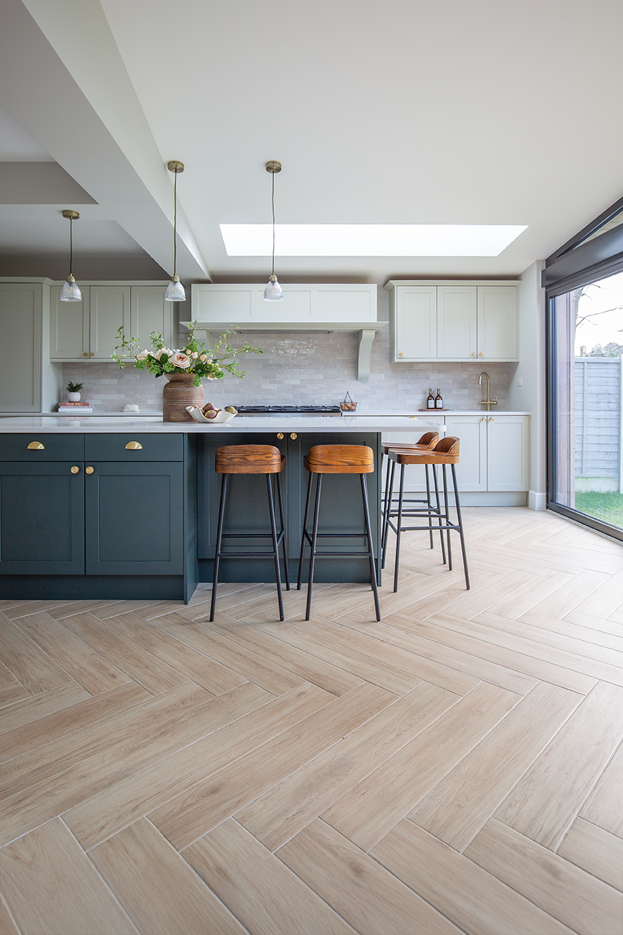A kitchen with a bar and stools and Falmouth Sandy Oak herringbone floor