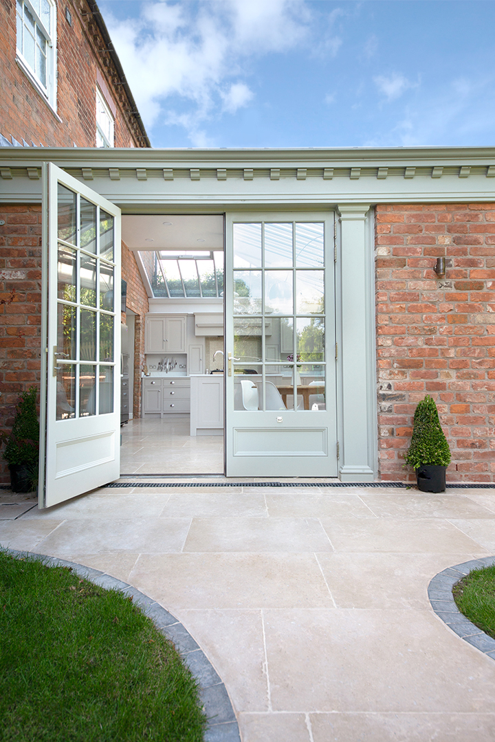 Green patio doors with limestone patio flooring outside
