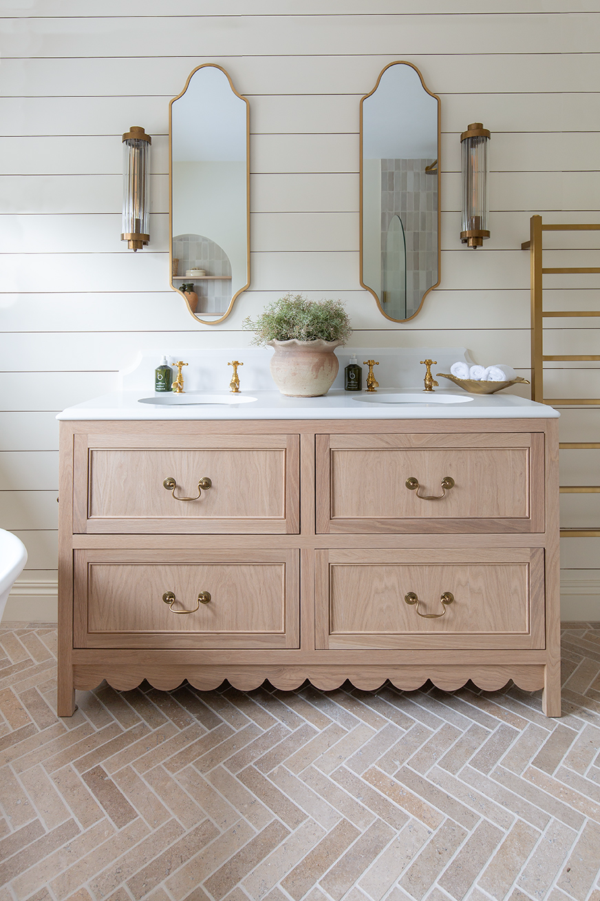 Dijon tumbled herringbone floor with a sink vanity with a mirror 