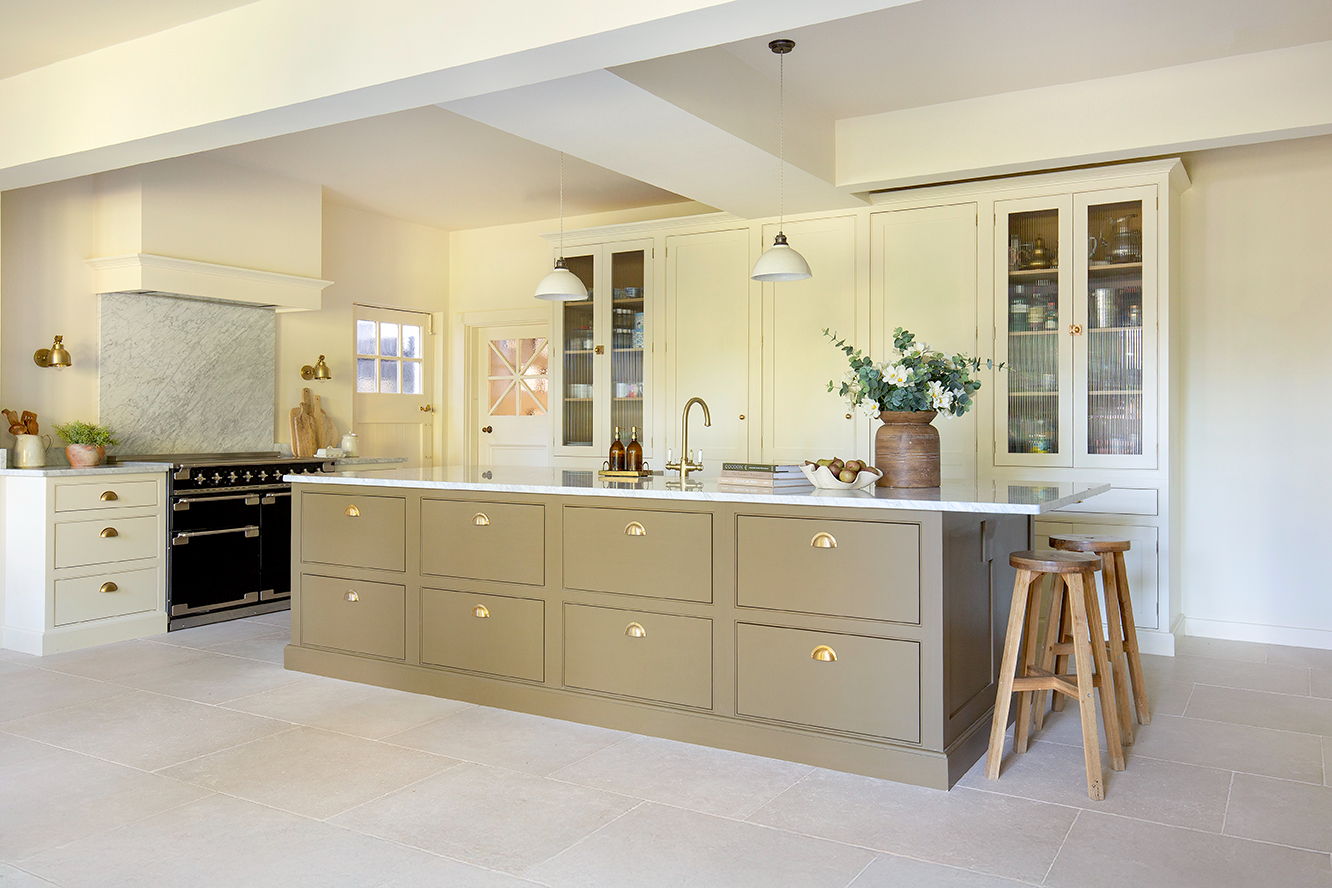A large, modern kitchen featuring a spacious island and wooden stools for seating.