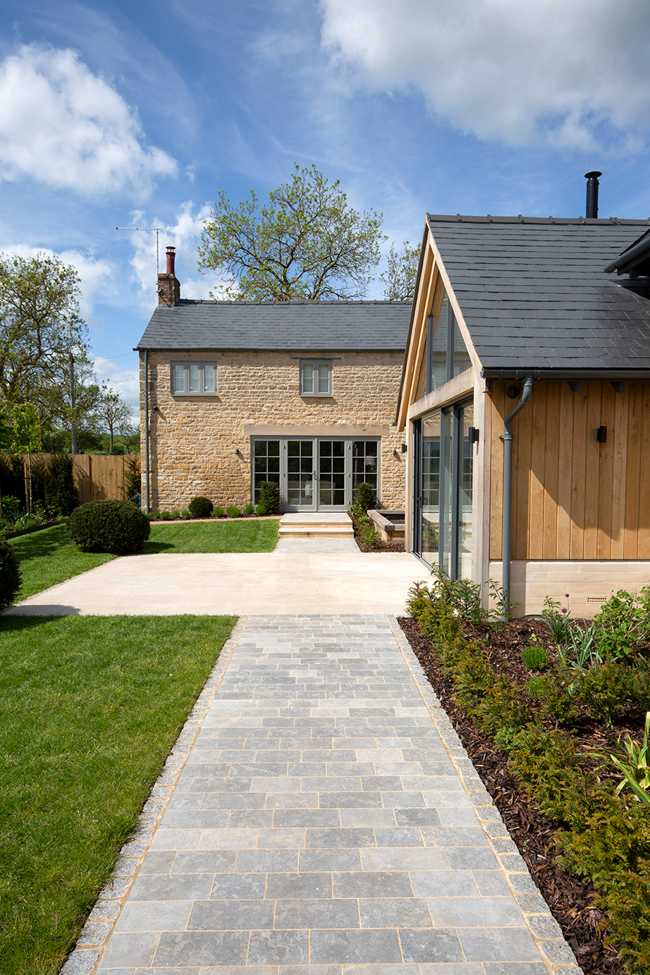 grey limestone cobble path with cotswold stone house and patio