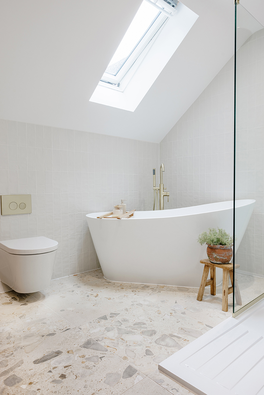 Modern bathroom tile inspiration featuring Orotelli Avorio Decor tiles on the floor paired with a white bath, showcasing subtle seashell detailing and a neutral, elegant palette.