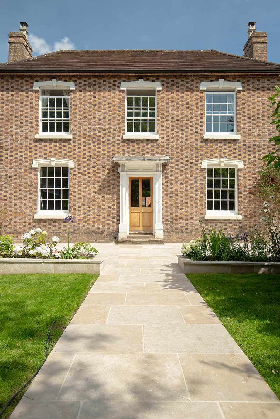 georgian house with beige flagstone pathway paving and planting