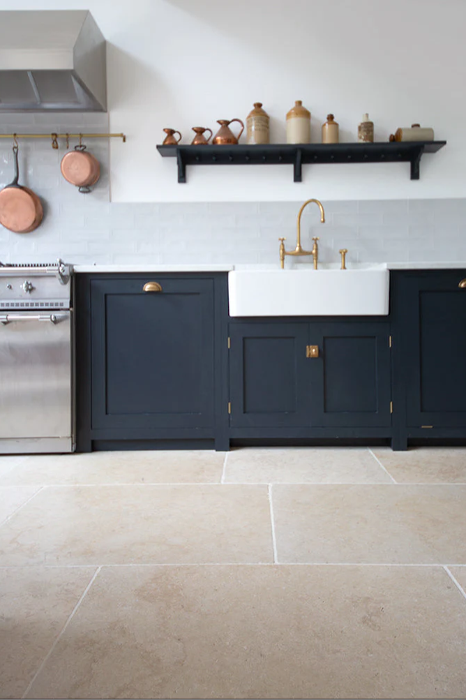 Monte Carlo limestone flooring with navy blue units with a shelf and copper pans 