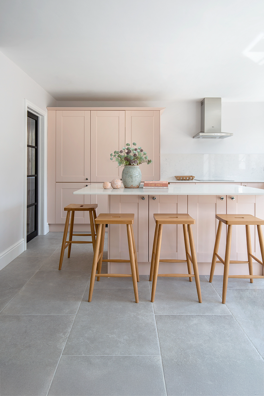 grey stone effect tiles with pink kitchen and island and oak wooden stools