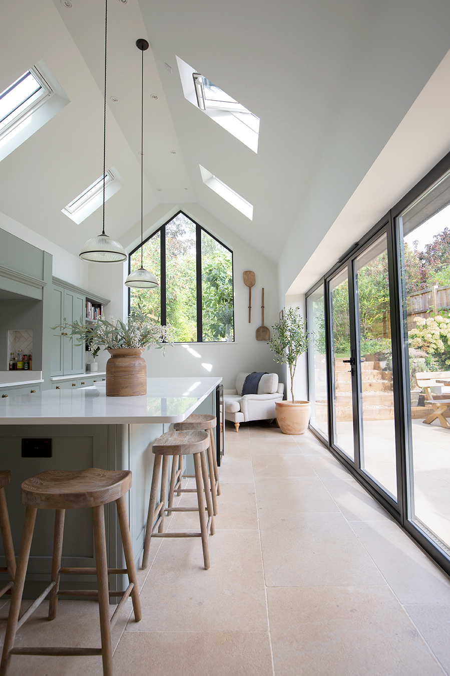 country style kitchen with pale blue cabinets large crittall doors and beige limestone flooring tiles