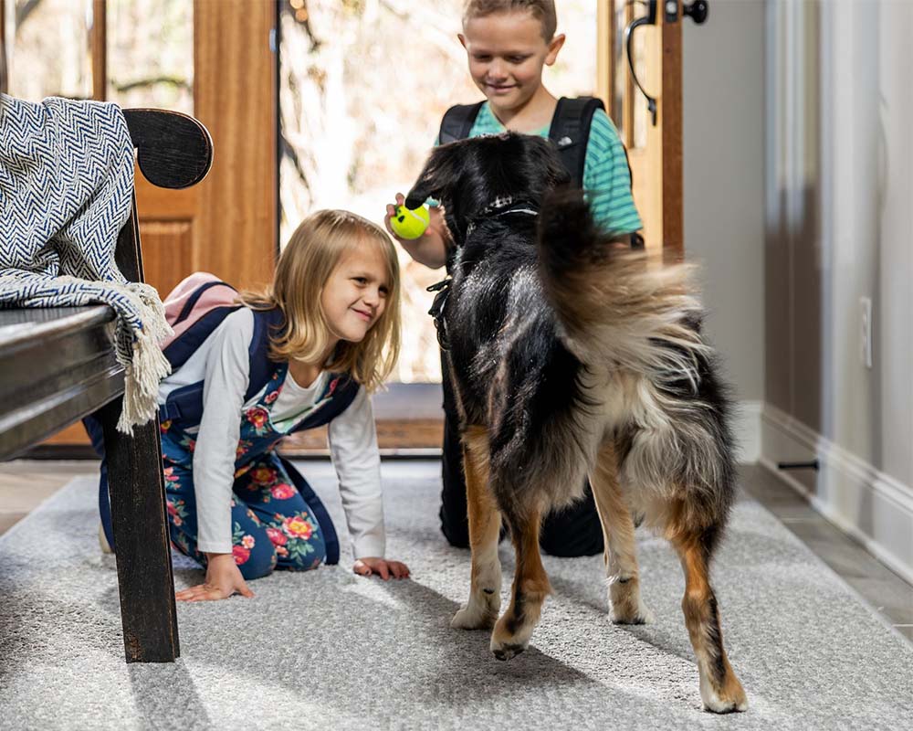 Girl and boy with boy on an area rug in from of doorway