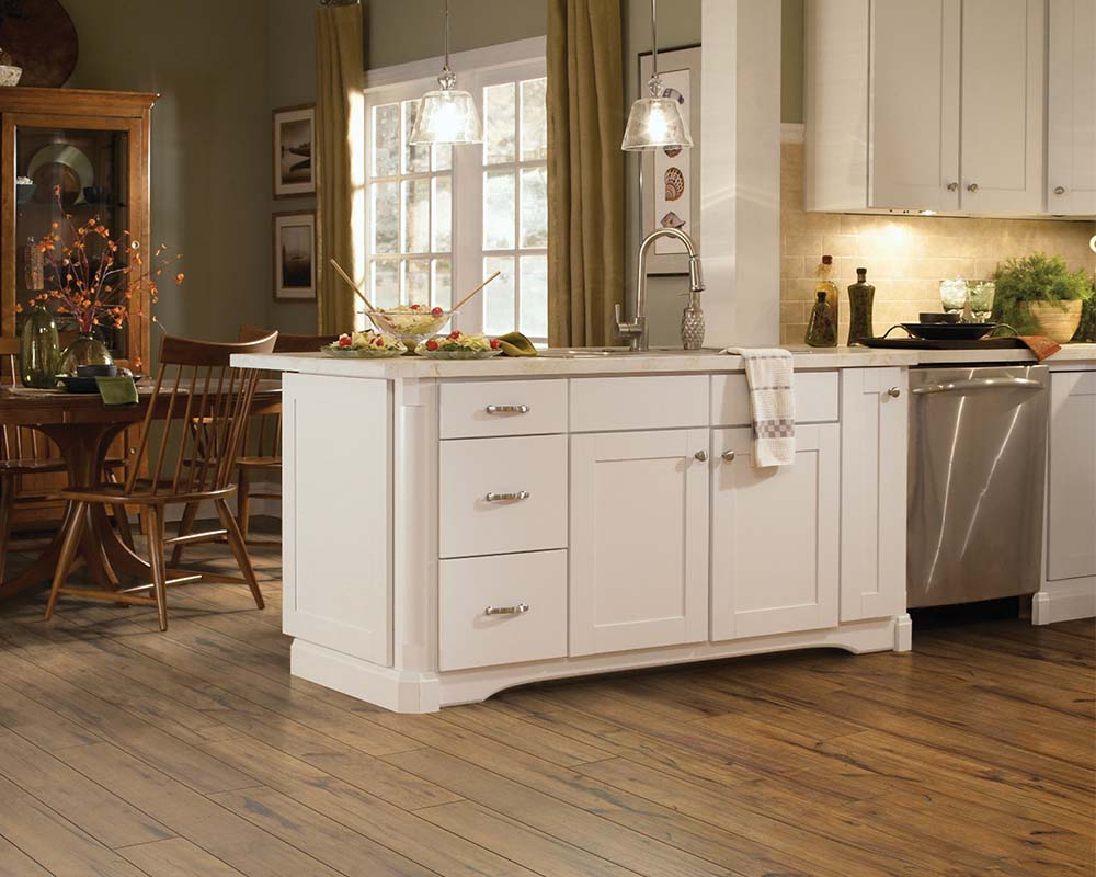 Beautiful kitchen with white cabinets and brown laminate floors.