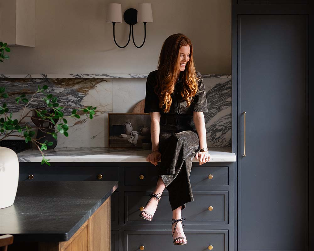 Designer Shelley Bates sitting on the counter in her newly remodeled kitchen.