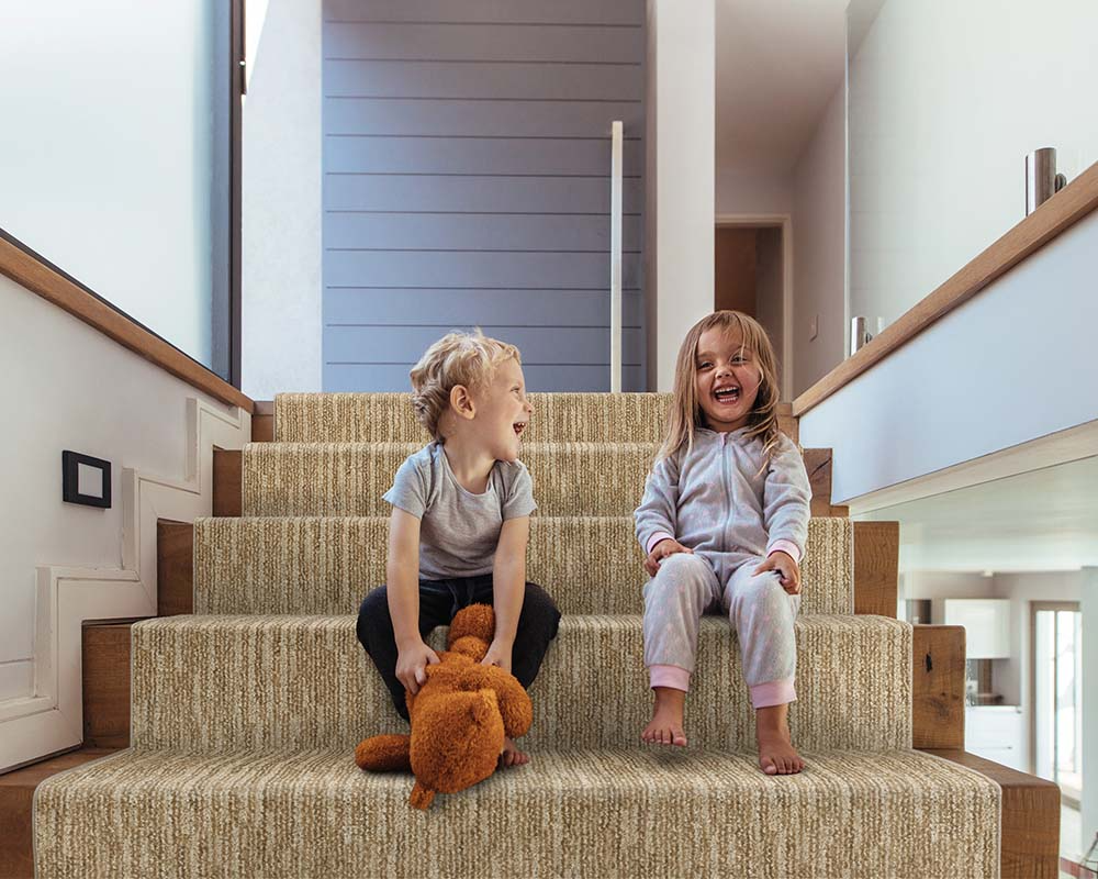 Girl and boy sitting on stairs with carpet stair runner