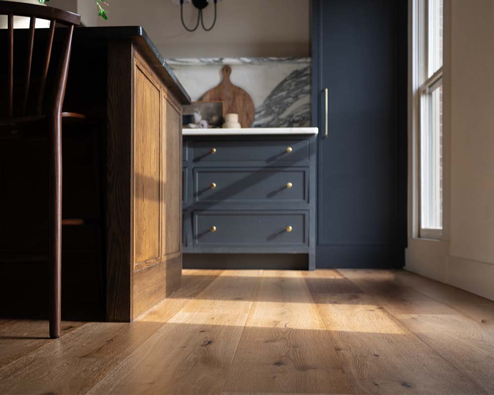 New hardwood flooring with blue cabinets in a remodeled kitchen