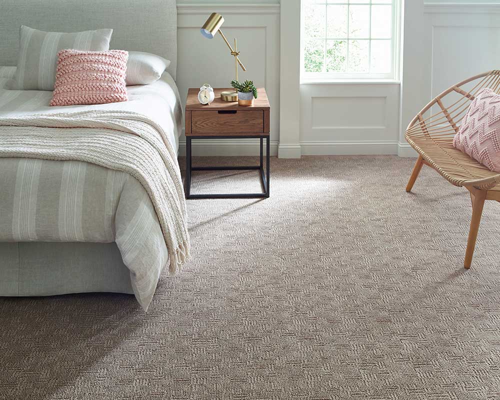 Light colored bedroom with pale pink patterned carpet. 
